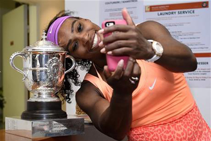 Serena Williams of the U.S. poses for a selfie with the trophy in the cloakroom after winning the French Open Tennis tournament against Lucie Safarova of the Czech Republic, at the Roland Garros stadium in Paris, France, Saturday, June 6, 2015. Williams won 6-3, 6-7, 6-2. (Corinne Dubreuil, FFT, Pool via AP)