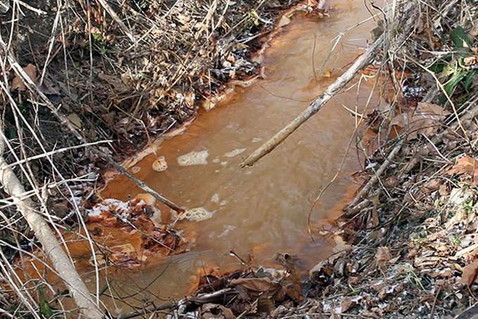 Water at the edge of the Clyde Mine discharge in East Bethlehem Township turns the water orangey red where it flows into Ten Mile Creek. (Photo by Natasha Khan)