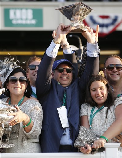 Ahmed Zayat, the owner of American Pharoah, holds up the Triple Crown trophy after he was awarded the August Belmont Trophy, held by his wife Joanne Zayat, left, after American Pharoah won the 147th running of the Belmont Stakes horse race at Belmont Park  in Elmont, N.Y. Zayat's  daughter Emma at right. American Pharoah is the first horse to win the Triple Crown since Affirmed won it in 1978. (AP Photo/Kathy Willens)