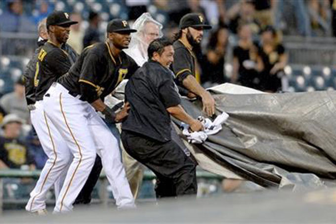 Pittsburgh Pirates' Andrew McCutchen, Gregory Polanco and Sean Rodriguez, from left, help grounds crew members put the tarp on the infield Tuesday night, July 7, 2015, in Pittsburgh as a storm blows into PNC Park during a baseball game between the Pirates and the San Diego Padres. (Matt Freed/Pittsburgh Post-Gazette via AP) 