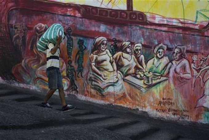 In this June 9, 2015 photo, a man descends steps while hauling a bag at, "Pedra do Sal" or "Rock of Salt", a site where slaves carved steps to climb a hill with heavy loads of salt, in Rio de Janeiro, Brazil. Brazil had more slaves than any other nation in the Americas, yet many experts say the nation has never truly acknowledged what 4 million Africans suffered through before, and after they landed on the nation's shores. (AP Photo/Felipe Dana)