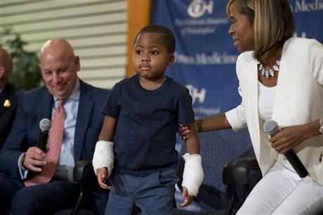 Double-hand transplant recipient eight-year-old Zion Harvey accompanied by Dr. L. Scott Levin, left, and his mother Pattie Ray, stands during a news conference Tuesday, July 28, 2015, at The Children’s Hospital of Philadelphia (CHOP) in Philadelphia.  (AP Photo/Matt Rourke)