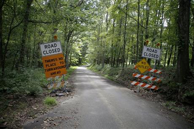Road signs are placed on the edge of the road leading to the home of Dr. Jan Casimir Seski in Murrysville, Pa., on Sunday, Aug. 2, 2015. Zimbabwe's National Parks and Wildlife Management Authority accused Seski of illegally killing a lion with a bow and arrow in April near Zimbabwe's Hwange National Park, without approval, on land where it was not allowed. (AP Photo/Keith Srakocic)