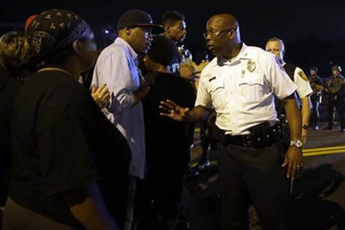 Ferguson Interim Police Chief Andre Anderson, right, tries to calm the crowd after a shooting near a protest in Ferguson, Mo., Monday, Aug. 10, 2015. The one-year anniversary of Michael Brown's death in Ferguson began with a march in his honor and ended with a protest that was interrupted by gunfire late Sunday night. (AP Photo/Jeff Roberson)