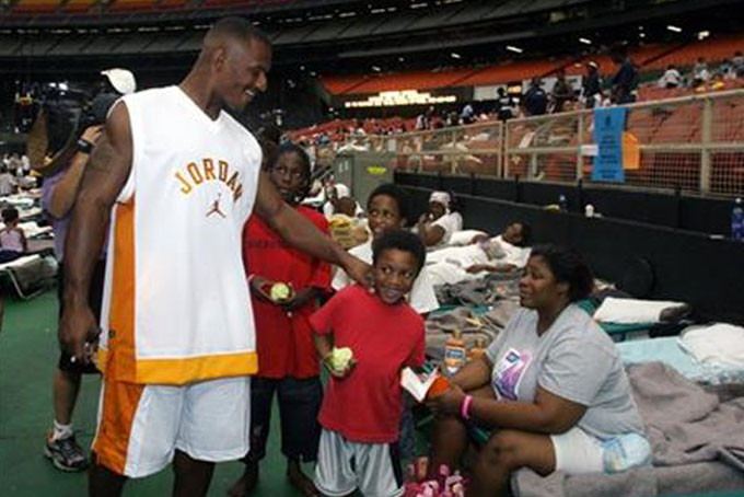 In this Sept. 3, 2005, file photo, New Orleans Saints receiver Joe Horn tries to boost morale while talking to an unidentified family at the Houston Astrodome where many displaced residents from New Orleans were being housed due to Hurricane Katrina. The 10-year anniversary of one of the most devastating hurricanes in U.S. history is a time of reflection for many connected to the Saints, whose return to New Orleans in 2006, following one season of displacement to San Antonio, became one of the ultimate feel-good stories in NFL history.(AP Photo/Donna Carson, File)