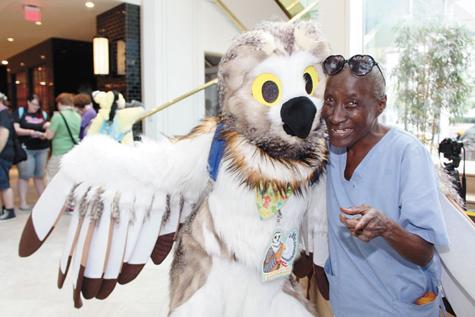 THE CHILD WITHIN COMES OUT—Shirley Butler, a retired Army vet and nurse, poses with Pemblery Owl. Butler had never seen the Furries or Anthropomorphic characters in person before and said, “I thought it was cool to see the parade, it was a joy to see every­one of them unique in every way imaginable.”