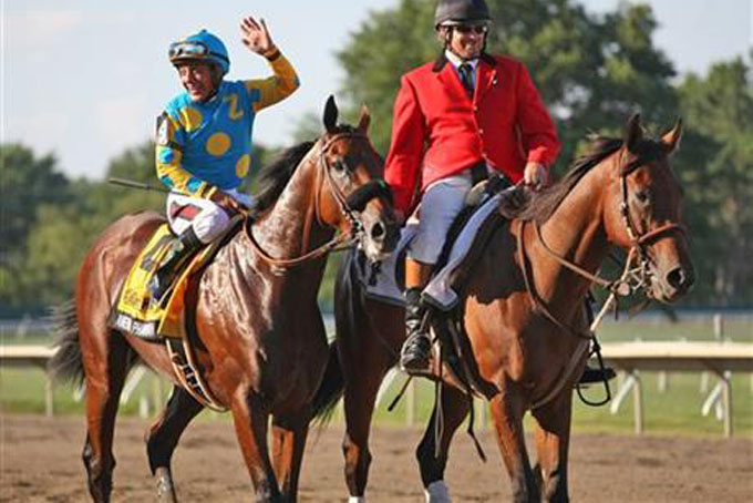 Jockey Victor Espinoza waves to the crowd aboard American Pharoah after winning the $1,750,000 Grade 1 William Hill Haskell Invitational at Monmouth Park in Oceanport, New Jersey on Sunday, Aug. 2, 2015. (Ryan Denver/EQUI-PHOTO via AP)