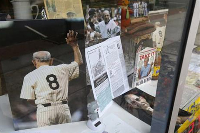 Memorabilia of New York Yankees Hall of Fame catcher Yogi Berra is on display at a store near Church of the Immaculate Conception before funeral services for the late baseball star, Tuesday, Sept. 29, 2015, in Montclair, N.J. The baseball legend known for his quirky sayings died Sept. 22. He was 90. (AP Photo/Julio Cortez) 