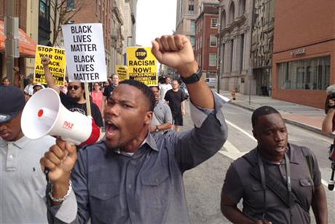 Pastor Westley West, from Faith Empowered Ministries, leads protesters as they march towards Pratt Street and the Inner Harbor, Wednesday, Sept. 2, 2015, in Baltimore, as the first court hearing was set to begin in the case of six police officers criminally charged in the death of Freddie Gray. Six police officers face charges that range from second-degree assault, a misdemeanor, to second-degree "depraved-heart" murder. (Lloyd Fox/The Baltimore Sun via AP) 