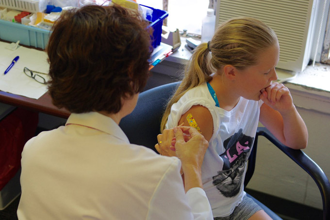 Kailey Byrnes, 11, winces as registered nurse Janet Stahlman administers an HPV shot at the Allegheny County Health Department vaccine clinic on Aug. 12. (Photo by Heather McCracken)
