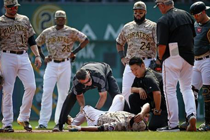 Pittsburgh Pirates' Jung Ho Kang, bottom center, is tended to by a team trainer after injuring his left leg turning a double play in the first inning of a baseball game against the Chicago Cubs in Pittsburgh, Thursday, Sept. 17, 2015. Kang left the game. (AP Photo/Gene J. Puskar)