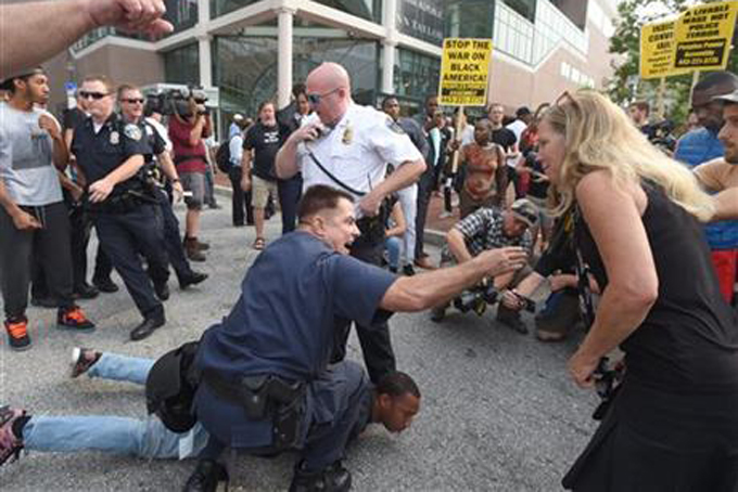 Baltimore Police try to control an angry protesters while detaining activist Kwame Rose as demonstrators marched to Pratt Street and the Inner Harbor, Wednesday, Sept. 2, 2015, in Baltimore, as the first court hearing was set to begin in the case of six police officers criminally charged in the death of Freddie Gray. Six police officers face charges that range from second-degree assault, a misdemeanor, to second-degree "depraved-heart" murder. (Lloyd Fox/The Baltimore Sun via AP) 