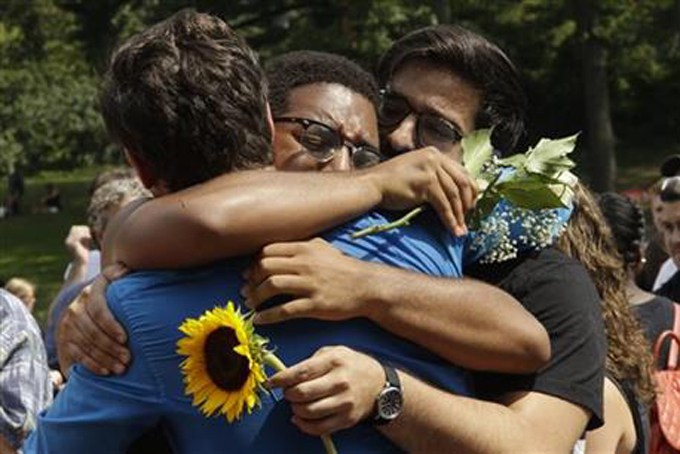 Friends embrace during a memorial gathering for Kyle Jean-Baptiste, Monday, Aug. 31, 2015, at Bethesda fountain in New York's Central Park. Baptiste, the first African-American and youngest person to ever play the role of Jean Valjean in "Les Misérables" on Broadway died after falling from a fire escape over the weekend, according to a show spokesman. He was 21. (AP Photo/Mary Altaffer)