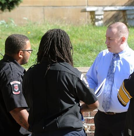 Acting Wilkinsburg School Board Superintendent Joseph Petrella, right, speaks with security guards outside Wilkinsburg High School after students were released from school because a student poured gasoline on a security guard. (Nate Guidry/Pittsburgh Post-Gazette via AP) 