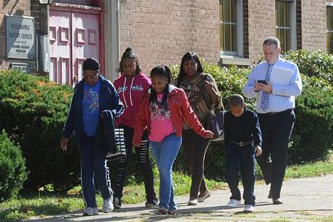 Acting Wilkinsburg School Board Superintendent Joseph Petrella, right, follows students and their parents after students were released from Wilkinsburg High School in Wilkinsburg, Pa., Monday, Sept. 21, 2015, because a student poured gasoline on a security guard. A spokesman for a Pennsylvania school district says the student attacked a security guard by pouring gasoline hidden inside a soda bottle on him. The spokesman says the student poured the fuel on the guard and the floor after 9 a.m. but didn't light it. The student is in police custody. The guard isn't believed to be seriously injured. (Nate Guidry/Pittsburgh Post-Gazette via AP) 