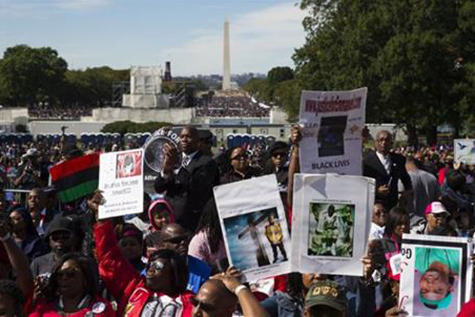 People cheer during a rally to mark the 20th anniversary of the Million Man March, on Capitol Hill, on Saturday, Oct. 10, 2015, in Washington. Waving flags, carrying signs and listening to speeches and songs, the crowd gathered at the U.S. Capitol and spread down the Mall under on a sunny and breezy fall day. (AP Photo/Evan Vucci)