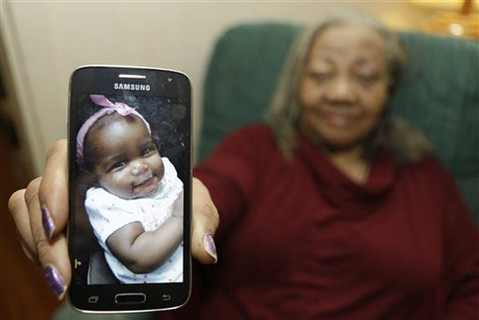 In this Wednesday, Oct. 28, 2015, photo, Beatrice Wakefield holds up a picture of her granddaughter Aavielle at her home in Cleveland. Wakefield was in a car with her daughter-in-law, her granddaughter Aavielle Wakefield and another child on the way to the grocery store when someone began firing at the vehicle, striking it numerous times. Aavielle, 5-months-old, sitting in her car seat, was fatally struck in the torso. No one else was injured. The killing remains unsolved. (AP Photo/Tony Dejak)
