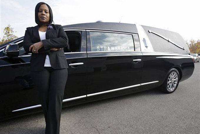 In this Thursday, Oct. 22, 2015, photo, Stephanie Strawbridge poses next to a hearse in Parma, Ohio. Frustrated and saddened by fatal gun deaths, members of the Greater Cleveland African-American Funeral Directors and Embalmers Association organized a procession of 25 hearses in mid-October that drove all around the city carrying signs with pointed messages that said, "Put the guns down: We don't want your business that bad," and "If you don't stop the shooting this may be your next ride." Strawbridge recently handled arrangements for a 5-year-old boy who was killed by crossfire while playing football behind his grandmother's home. (AP Photo/Tony Dejak)