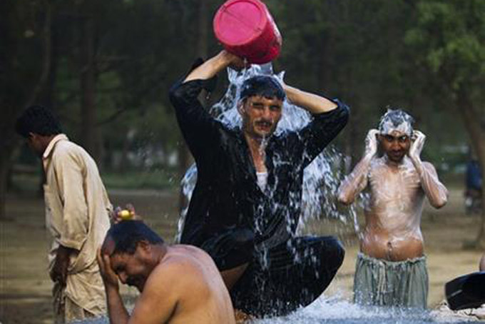 COOLING OFF--In this June 3, 2013 file photo, Pakistani laborers bathe at a leaked water hydrant at the end of a day on the outskirts of Islamabad. (AP Photo/B.K. Bangash, File)