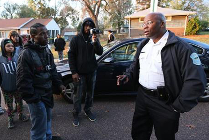 In this Oct. 28, 2015 file photo, Interim Ferguson, Mo., Police Chief Andre Anderson, right, talks with people in Normandy, Mo. (Chris Lee/St. Louis Post-Dispatch via AP, File) 