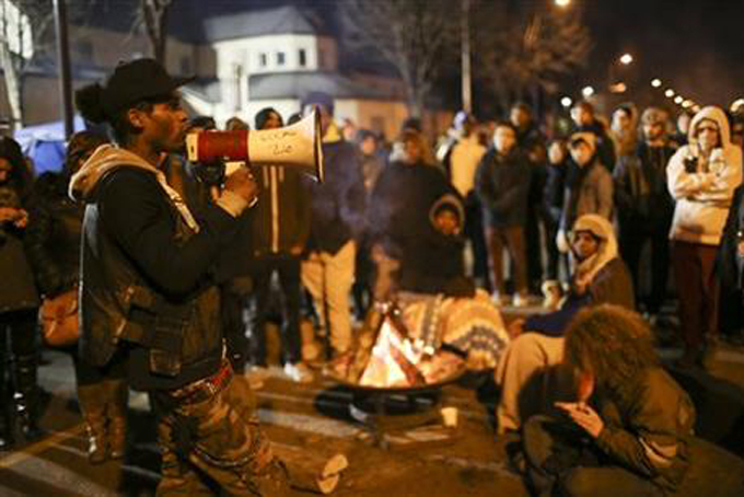 A demonstrator speaks about his encounter with attackers who were shooting at five protesters near the Minneapolis Police 4th Precinct earlier in the night, as protesters gather in front of the precinct in Minneapolis on Tuesday, Nov. 24, 2015. (Jeff Wheeler/Star Tribune via AP)