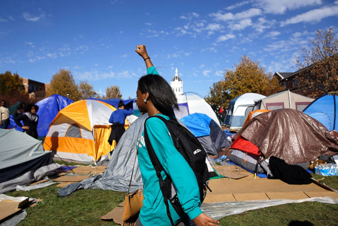 A woman passes a tent encampment set up by student protesters following an announcement that University of Missouri System President Tim Wolfe is resigning Monday, Nov. 9, 2015, at the university in Columbia, Mo.  (AP Photo/Jeff Roberson)