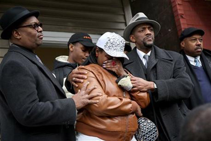LaTarsha Jones, center, the daughter of Bettie Jones, is comforted by family and friends during a news conference on Sunday, Dec. 27, 2015, in front of the house where Bettie Jones was killed Saturday in the West Garfield Park neighborhood of Chicago. (Nancy Stone/Chicago Tribune via AP) 