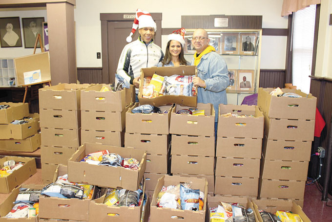 CHRISTMAS BASKETS—Park Place AME Church, located at 215 E. 10th Ave., in Homestead, hosted its Joseph McCain’s Christmas Food Basket Distribution. For two days, the church distributed boxes of food that included most of the fixings needed to make a Christmas meal for the family. The distribution took place on Dec. 19-20. Pictured above, from left: Joseph Mccain, Tanika Taylor and Pastor James H. Harris hold one of the 1400 boxes that were donated to the community. (Photos by J.L. Martello) 