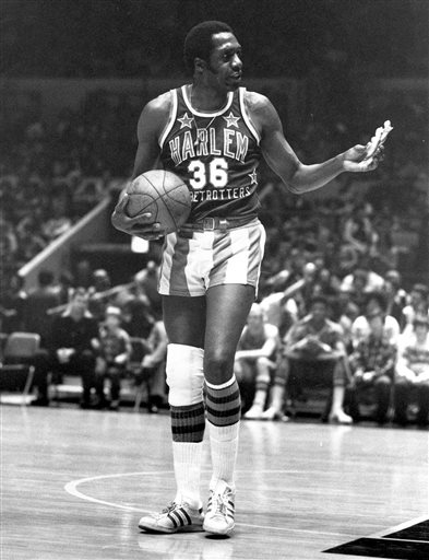 In this Feb. 18, 1978, file photo, Meadowlark Lemon, of the Harlem Globetrotters basketball team, offers a pretzel to a referee during a game at New York's Madison Square Garden. Lemon, known as the Globetrotters' "clown prince" of basketball, died Sunday, Dec. 27, 2015, in Scottsdale, Ariz. He was 83. (AP Photo/Suzanne Vlamis, File)