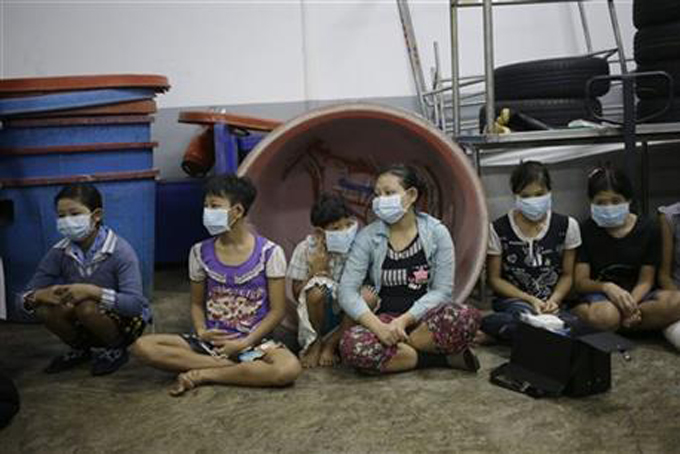 In this Monday, Nov. 9, 2015 photo, children and teenagers sit together to be registered by officials during a raid on a shrimp shed in Samut Sakhon, Thailand.  (AP Photo/Dita Alangkara) 