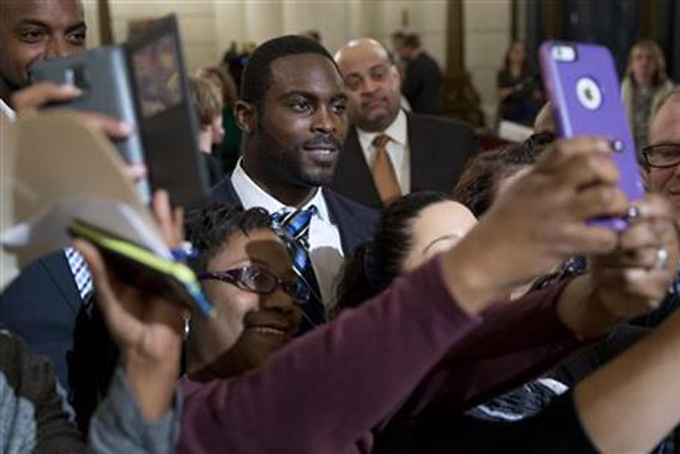 Pittsburgh Steelers quarterback Mike Vick poses for selfies after a news conference Tuesday, Dec. 8, 2015, at the state Capitol in Harrisburg, Pa. (AP Photo/Matt Rourke)