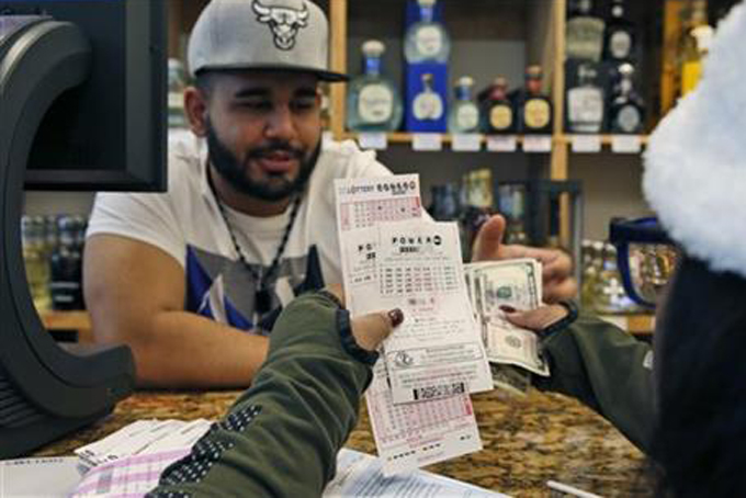 Samir Akhter, the owner of Penn Branch Liquor, exchanges money for Powerball tickets, Saturday, Jan. 9, 2016 in Washington. Officials say it's increasingly likely that someone will win the $900 million Powerball jackpot, which grew by $100 million just hours before Saturday night's drawing. (AP Photo/Alex Brandon)