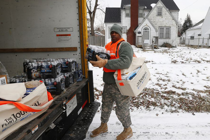 Michigan National Guard Specialist Lonnie Walker unloads bottled water and filters to distribute to residents, Thursday, Jan. 21, 2016 in Flint, Mich. The National Guard, state employees, local authorities and volunteers have been distributing lead tests, filters and bottled water during the city's drinking water crisis. (AP Photo/Paul Sancya)