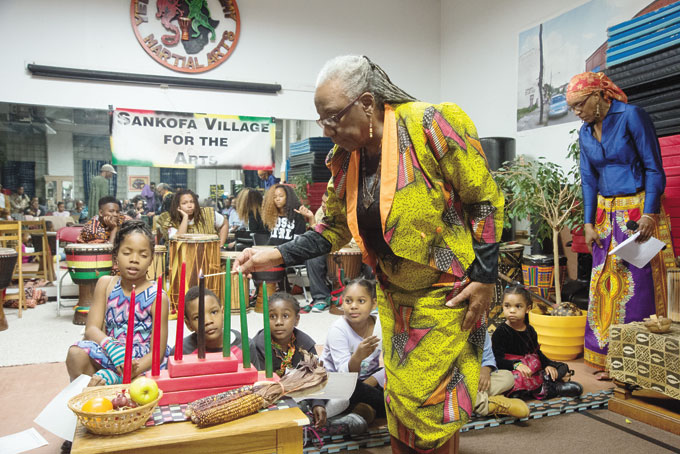 GLADYS NESBITT lights the unity candles at Sankofa Village’s Kwanzaa 2015. (Photos by Gail Manker)