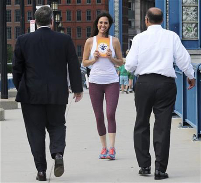  In this Aug. 25, 2015, photo, Sara DiVello carries her book "Where in the OM Am I?" as she passes two businessmen in the Financial District of Boston.  (AP Photo/Charles Krupa)