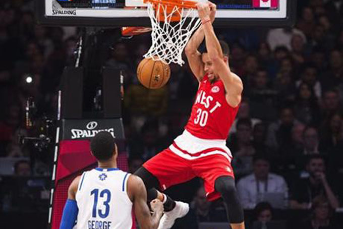 Western Conference's Stephen Curry, of the Golden State Warriors, (30) slam dunks the ball past Eastern Conference's Paul George, of the Indiana Pacers (13) during the first half of the NBA all-star basketball game, Sunday, Feb. 14, 2016 in Toronto. (Mark Blinch/The Canadian Press via AP) 