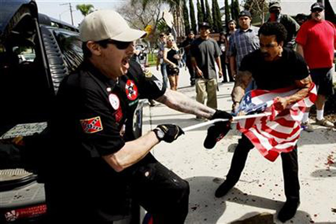 A Ku Klux Klansman, left, fights a counter protester for an American flag after members of the KKK tried to start a "White Lives Matter" rally at Pearson Park in Anaheim on Saturday, Feb. 27, 2016. The event quickly escalated into violence and at least two people had to be treated at the scene for stab wounds. (Luis Sinco/Los Angeles Times via AP)