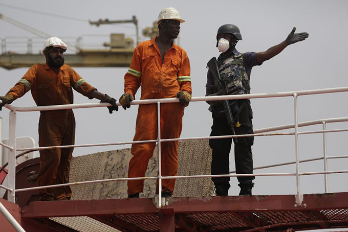 A Nigerian naval officer, right, gestures as he speaks to some of the rescued crew members of the hijacked Panama-flagged Maximus vessel in Lagos, Nigeria Monday, Feb. 22, 2016. Nigerian sailors rescued a hijacked oil tanker in a dramatic night-time rescue in which they killed one pirate, the Nigerian navy announced as it escorted the ship into Lagos harbor Monday. (AP Photo/Sunday Alamba)