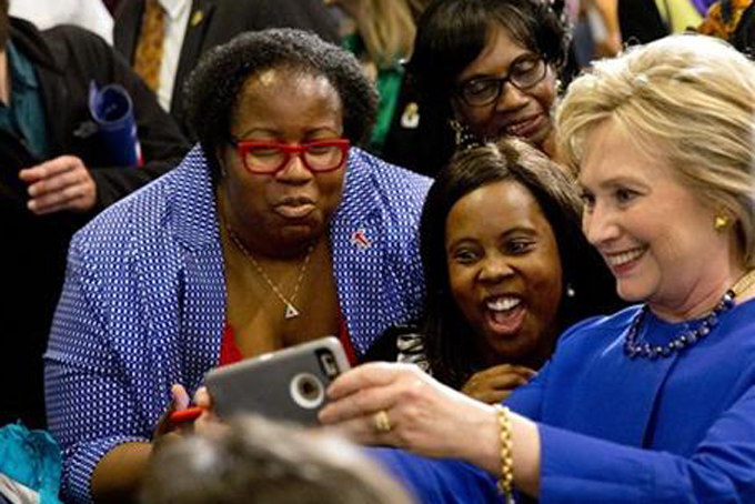 FILE - In this Feb. 23, 2016 file photo, Democratic presidential candidate Hillary Clinton takes pictures with supporters after a campaign event at the Central Baptist Church in Columbia, S.C. During a primary season that has proved surprisingly competitive, bombarded with persistent critiques about her likeability and trustworthiness, Clinton has maintained a strong bond with one significant block of Democratic Party voters. Black women. (AP Photo/Jacquelyn Martin, File)
