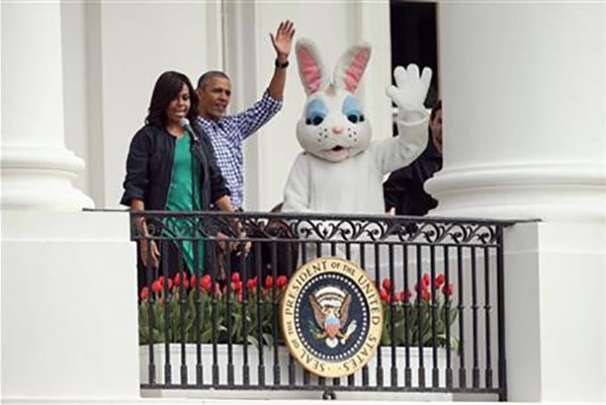 President Barack Obama, accompanied by first lady Michelle Obama and the Easter Bunny wave from the Truman Balcony of the White House in Washington, Monday, March 28, 2016, to participants on the South Lawn during the annual White House Easter Egg roll. (AP Photo/Andrew Harnik)