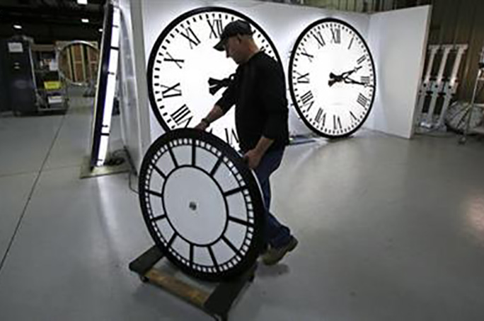 Dan LaMoore wheels a clock away from the test area as it is prepared to be shipped to a Tennessee school at the Electric Time Company in Medfield, Mass., Thursday, March 10, 2016. (AP Photo/Charles Krupa)