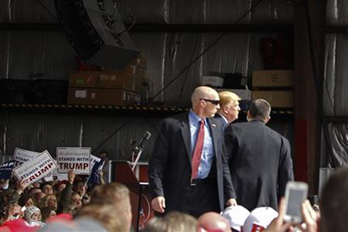 Secret Service agents guard Republican presidential candidate, businessman Donald Trump, on the stage after a man tried to breach the security buffer at his campaign event at the Wright Brothers Aero Hangar Saturday, March 12, 2016, in Vandalia, Ohio. (AP Photo/Kiichiro Sato)