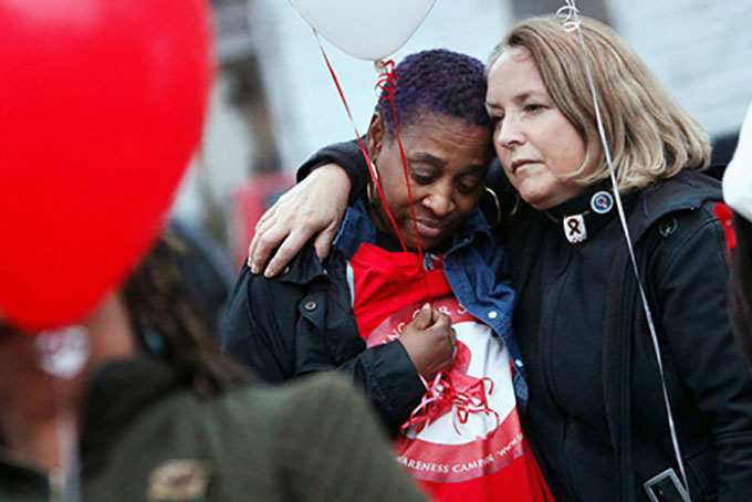 From left, Angela Vick and Julieta Giner hug before releasing balloons to mark World AIDS Day on Tuesday, Dec. 1, 2015 in Durham, N.C. Vick, a motivational speaker, has been HIV-positive for nearly eight years. "It's important to stop the stigma," Vick said. (Christine T. Nguyen/The Herald-Sun via AP)