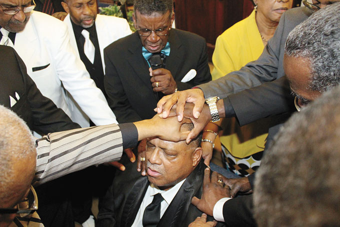 PROVIDING SPIRITUAL SUPPORT—Pastors and deacons lay their hands on the deacon and pray over him as he is being ordained.