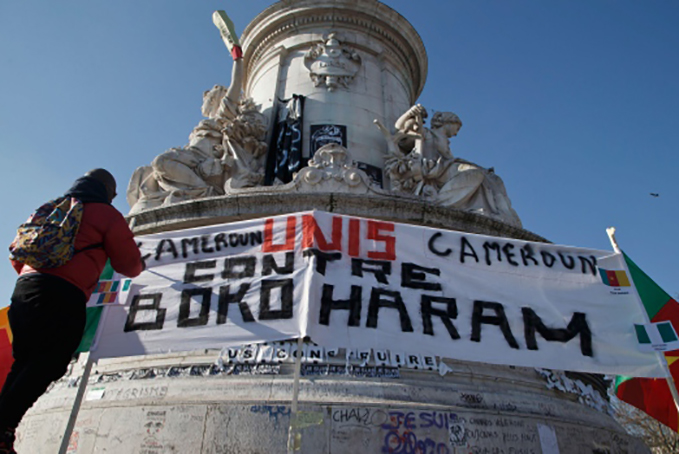 UNITED—A Cameroonian man living in exile in France adjusts a banner which reads, ‘Cameroon united against Boko Haram,’ at the Republique plaza in Paris, Saturday, Feb. 7, 2015. (AP / Michel Euler)
