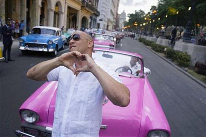 FILE - In this May 3, 2016, file photo, U.S. Actor Vin Diesel flashes a heart-in-hand to the crowd ahead of the presentation of fashion designer Karl Lagerfeld's "cruise" line for fashion house Chanel, along Paseo del Prado street in Havana, Cuba. The mostly foreign audience arrived in specially hired classic American cars. Havana residents had to watch from behind police lines more than a block away. (AP Photo/Ramon Espinosa, File)