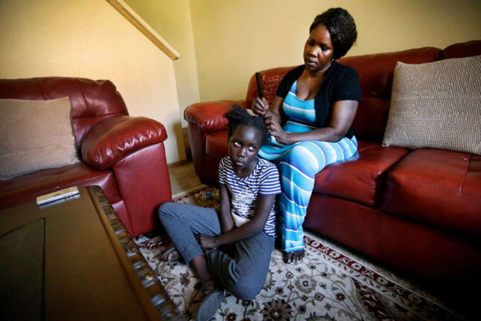  In this Wednesday, June 22, 2016 photo, Achan Agit, of Des Moines, Iowa, braids nine-year old Esta James' hair, in Des Moines. (AP Photo/Charlie Neibergall)