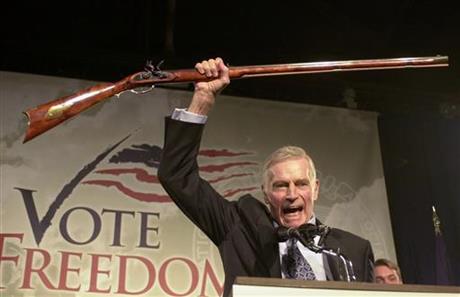 FILE - In this Monday, Oct. 21, 2002 file photo, National Rifle Association President Charlton Heston holds up a rifle as he addresses gun owners during a "get-out-the-vote" rally in Manchester, N.H. In May 1977, as the NRA entered its second century, it faced an identity crisis: Was it a coalition of sportsmen, or a political powerhouse? Leaders were set on the former, drawing up plans to move its headquarters from Washington to Colorado and to retreat from politics. Some of its most fiery members disagreed, staging a revolt that night that stretched into the next morning, and remade the group's leadership. Plans for a westward move were scuttled, and a rightward move politically was sealed. (AP Photo/Jim Cole)