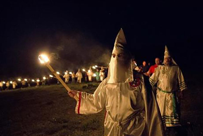 In this Saturday, April 23, 2016 photo, members of the Ku Klux Klan participate in cross burnings after a "white pride" rally in rural Paulding County near Cedar Town, Ga. Born in the ashes of the smoldering South after the Civil War, the KKK died and was reborn before losing the fight against civil rights in the 1960s. Membership dwindled, a unified group fractured, and one-time members went to prison for a string of murderous attacks against blacks. Many assumed the group was dead, a white-robed ghost of hate and violence. (AP Photo/John Bazemore)