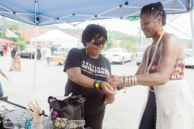 MORE THAN FOOD—Energy assistant employee Lorraine Cross with a bracelet at Cabochons and More jewelry booth at the Grand opening of the Homewood Community Farmers Market. Cabochons was one of the few venders not selling food.